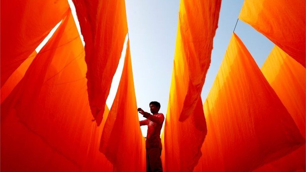 A worker dries fabrics after applying color at a dye factory in Narayanganj, Bangladesh, January 13, 2021.