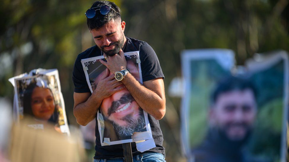 Rudy Glazer, whose brother Ranani was killed on October 7, hugs a photo of his brother at the site of the Nova festival