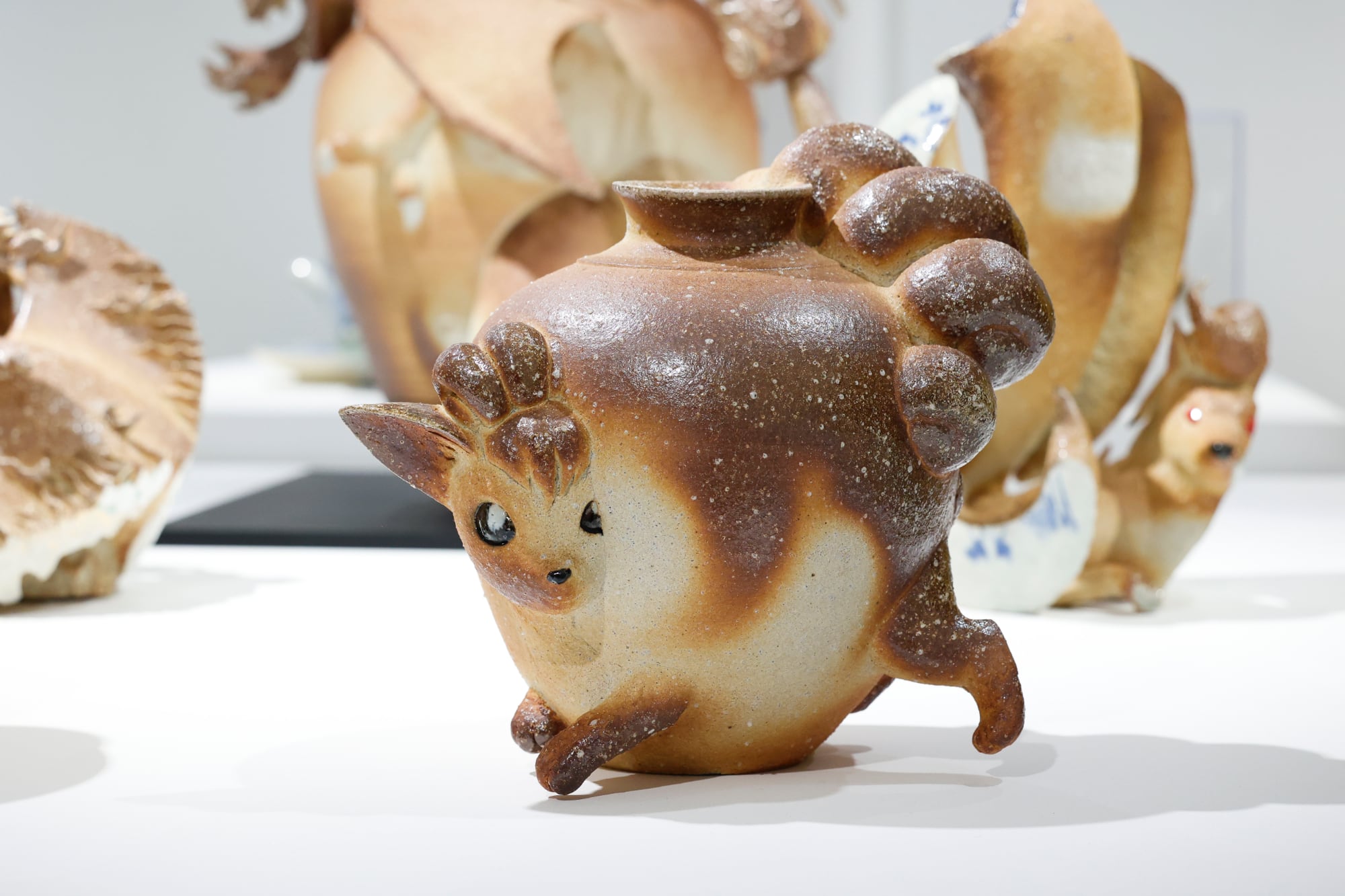 a ceramic jar with a deer-like character emerging from the sides