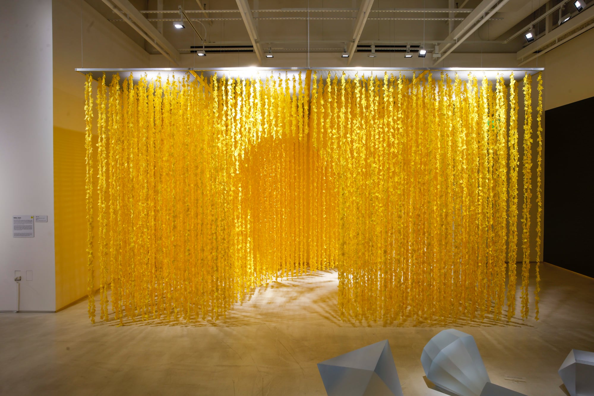 an installation with a tunnel through dangling yellow tendrils