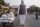 A photograph showing a street scene in India, with a large cutout poster of the Prime Minister of India, Narendra Modi, in the median of a street while people drive and ride past.