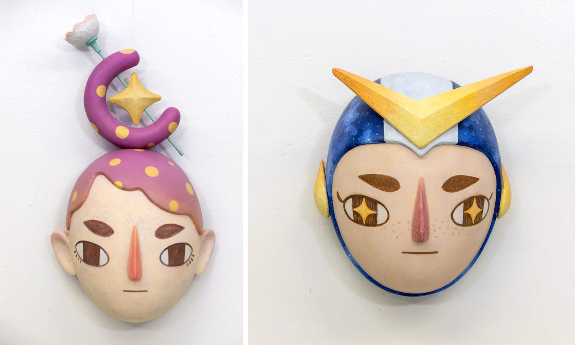 Left: a sculpture of a head with purple hair shaped into a crescent moon. Right: a sculpture of a head with a yellow V on its headwear.