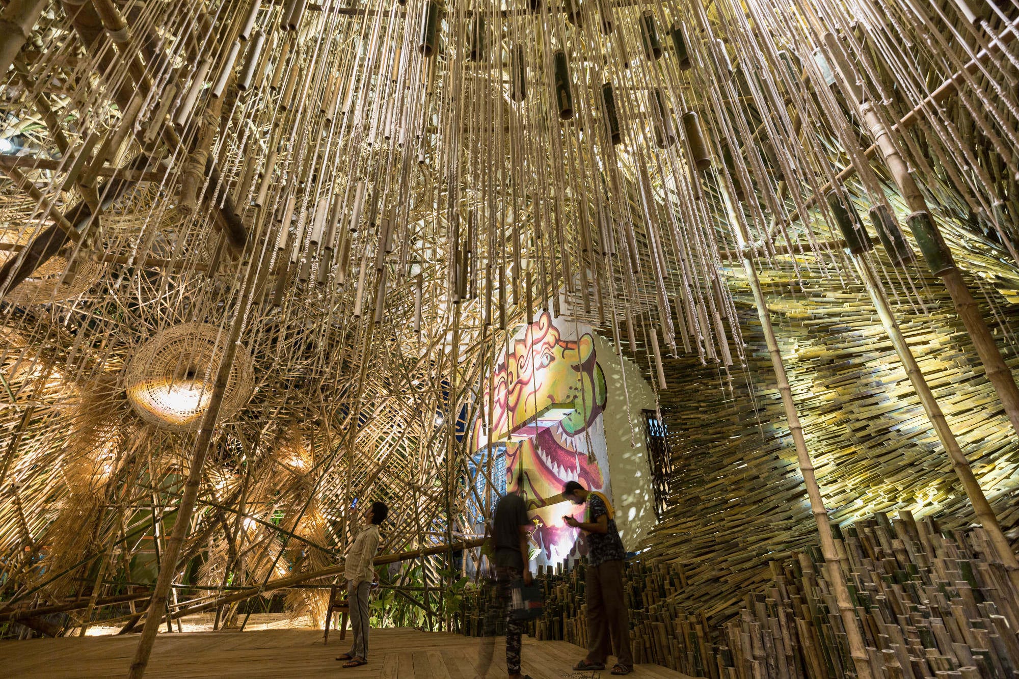 people wander through a large bamboo installation
