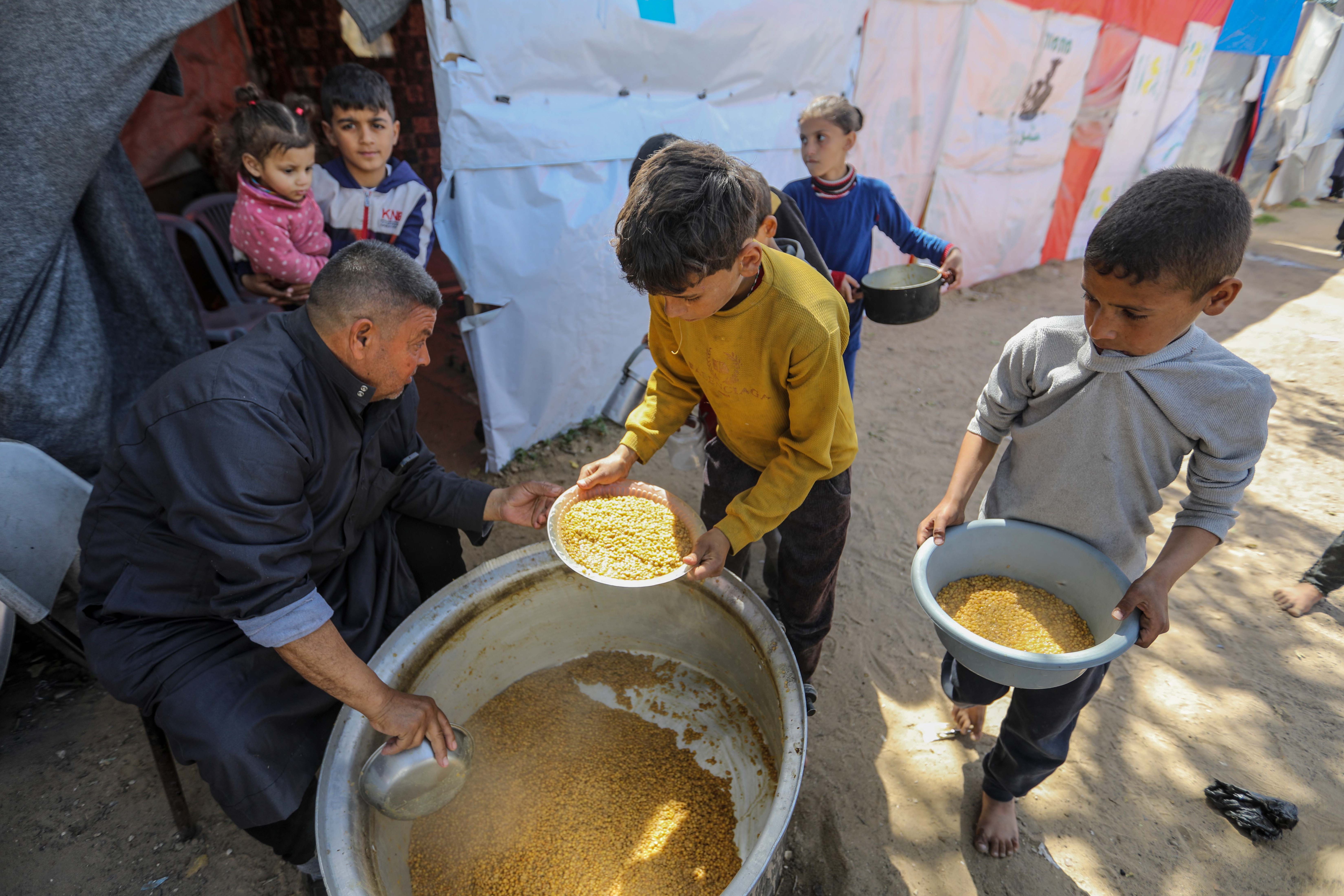 

<p>Citizens queue for food that is cooked in large pots and distributed for free in Rafah, southern Gaza</p>
<p>” height=”4394″ width=”6590″ layout=”responsive” i-amphtml-layout=”responsive”><i-amphtml-sizer slot=
