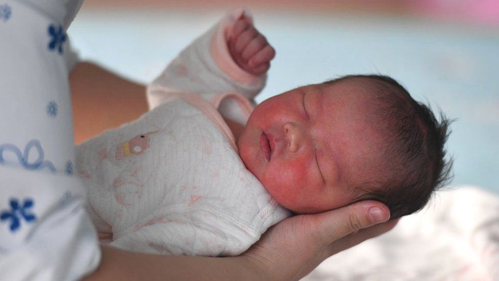 A maternity nurse performs a health check on a newborn baby