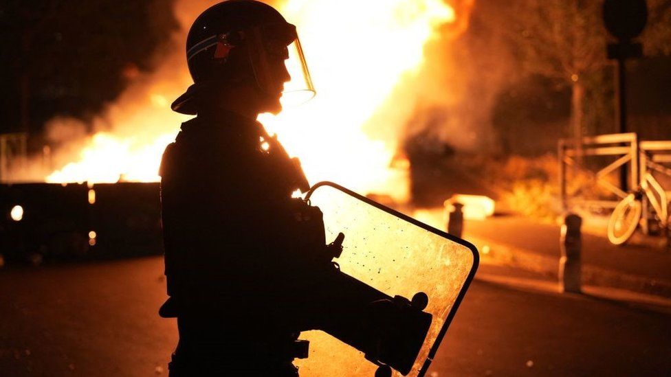 A firefighter looks on as vehicles burn following riots in Nanterre, west of Paris, on June 28, 2023, a day after a 17-year-old boy was shot in the chest by police at point-blank range in this western suburb of Paris