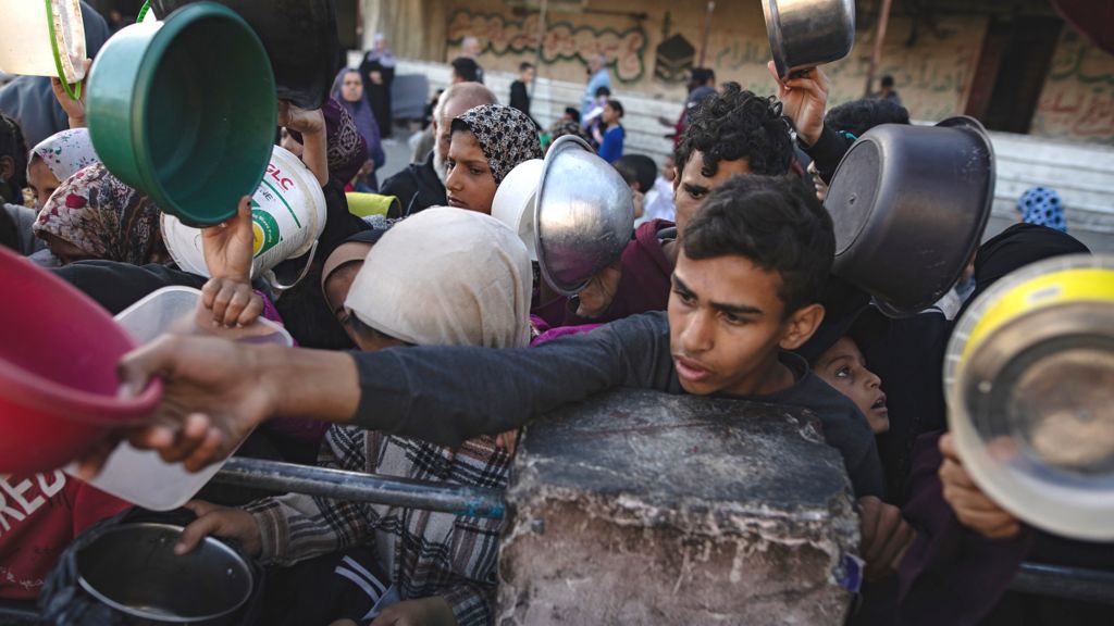 Displaced Palestinians gather to collect food in Rafah on 12 March